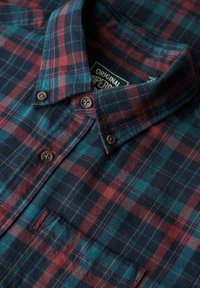 Geruit flanellen overhemd met een blauw, rood en donker marinepatroon, knoopsluiting, kraag met knopen en Superdry-label, met bruine knopen en zachte textuur.