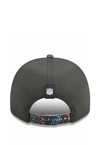 Schwarze Baseballmütze aus perforiertem Stoff, verstellbarer Riemen mit buntem Farbklecks-Muster und NFL-Logo-Tag auf der Rückseite.