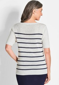 Leichter Strickpullover mit kurzen Ärmeln. Grundfarbe Creme mit horizontalen dunkelblauen Streifen. Gerippter Saum und Ausschnitt.