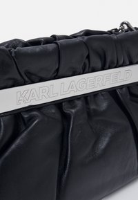Clutch bag in pelle nera con placca metallica argentata incisa "KARL LAGERFELD" lungo il bordo superiore.
