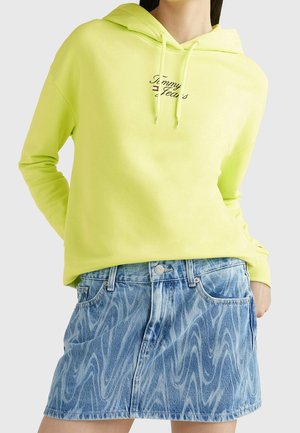 Neon gul hoodie med dragsnören och logga, ihop med en denimkjol med vågmönster, strukturerad passform och fem fickor.