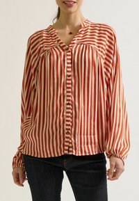 Rood en crèmekleurig gestreepte blouse met een V-hals, knopen aan de voorkant en lange, geplooide mouwen. Gemaakt van lichte stof met een zachte textuur.