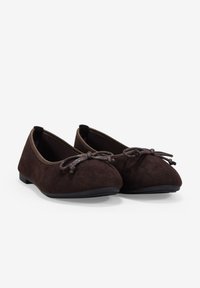 Bailarinas de ante marrón con punta redondeada, suela plana y detalle de lazo decorativo en la parte frontal. Textura suave y diseño sencillo.