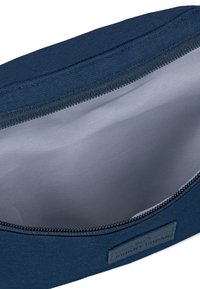 Marineblaue Tasche aus strukturiertem Stoff mit glattem Innenfutter, ausgestattet mit einem Reißverschluss und einem kleinen Logotag an der Seite.