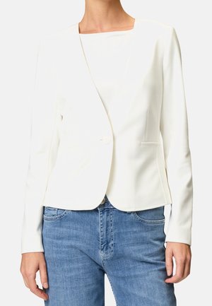 Hvid blazer med en struktureret overflade, med en enkelt knaplukning, skrå klapper og to sidelommer. Sammen med blå jeans.