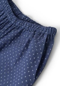 Marineblaues Gewebe mit kleinem weißen Blumenmuster, gerafftem elastischem Taillenbund und weicher Textur mit subtilen Falten.