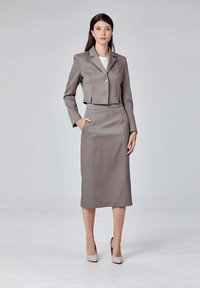 Blazer gris ajusté avec un seul bouton et un design court, associé à une jupe crayon de la même couleur. Texture lisse, manches longues.