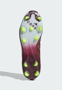 Suela de botas de fútbol color carmesí con tacos amarillos, con una superficie texturizada y la marca "COPA" cerca del talón, efecto degradado de rojo a transparente.