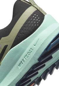 Baskets en mesh noir avec accents vert olive, semelle en mousse menthe texturée, et logo Nike distinct. Présente un motif perforé sur la tige.