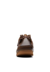 Zapato náutico de cuero marrón con punta redondeada, costuras en contraste y suela de goma color beige. Presenta cordones en el empeine para un ajuste seguro.