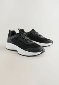 Mustad jooksujalatsid võrkmaterjalist pealiskattega ja valge tallaga. Omadusteks on erinevat värvi paelad ning tekstuuriga ninatükk. Madala lõikega disain.