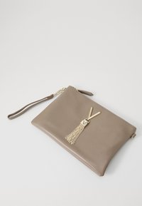 Leather clutch bag in tan, featuring a gold-tone V hardware and a chain tassel accent. Zipper closure and wrist strap included.