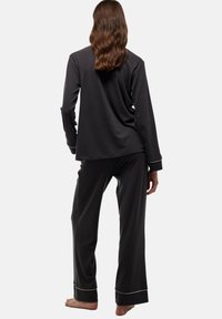 Haut à manches longues gris foncé et pantalon assorti en tissu doux. Le pantalon présente une bordure contrastante blanche au niveau des poignets.