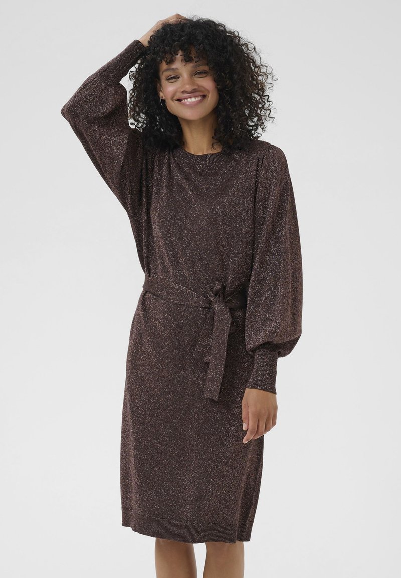 Robe en tricot marron avec des détails brillants, manches bouffantes longues et une ceinture assortie nouée à la taille. L'ourlet tombe juste en dessous des genoux.