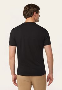 Zwarte katoenen T-shirt met korte mouwen, ronde halslijn, met een klein logo-detail op de achterkant van de hals. Soepele textuur.