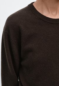 Ciemnobrązowy sweter dziany z okrągłym dekoltem i długimi rękawami, charakteryzujący się miękką fakturą i casualowym designem.