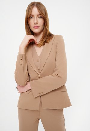 Blazer beige con escote en V, tres botones y mangas largas, hecho de tejido texturizado. Cuenta con bolsillos laterales y un ajuste entallado.