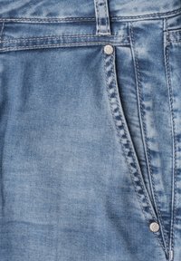 Close-up of light blue denim jeans showing front pocket, belt loop, stitching, and metal rivet detail.