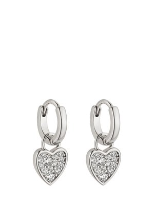 Silberne Creolen mit hängenden, herzförmigen Anhängern, besetzt mit kleinen klaren Edelsteinen, auf weißem Hintergrund präsentiert.