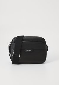 Borsa a tracolla nera in materiale sintetico testurizzato, con hardware argentato, tracolla regolabile, caratterizzata da una placca logo frontale e chiusura con zip.