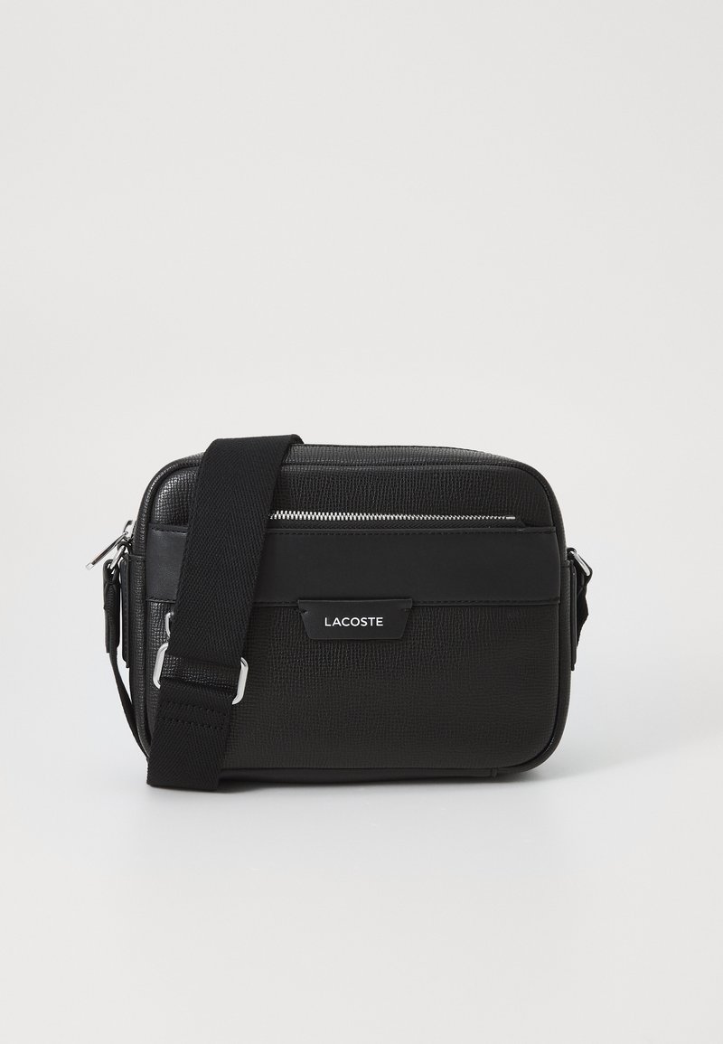 Borsa a tracolla nera in materiale sintetico testurizzato, con hardware argentato, tracolla regolabile, caratterizzata da una placca logo frontale e chiusura con zip.