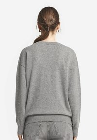 Szary sweter z dzianiny o luźnym kroju, okrągłym dekolcie i prążkowanym pasie. Miła w dotyku faktura oraz opuszczone szwy ramion dla wygody.