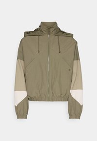 Light olive green zip-up jacket with a hood, drawstrings, elastic cuffs and hem, and beige and white color blocks on the sleeves.