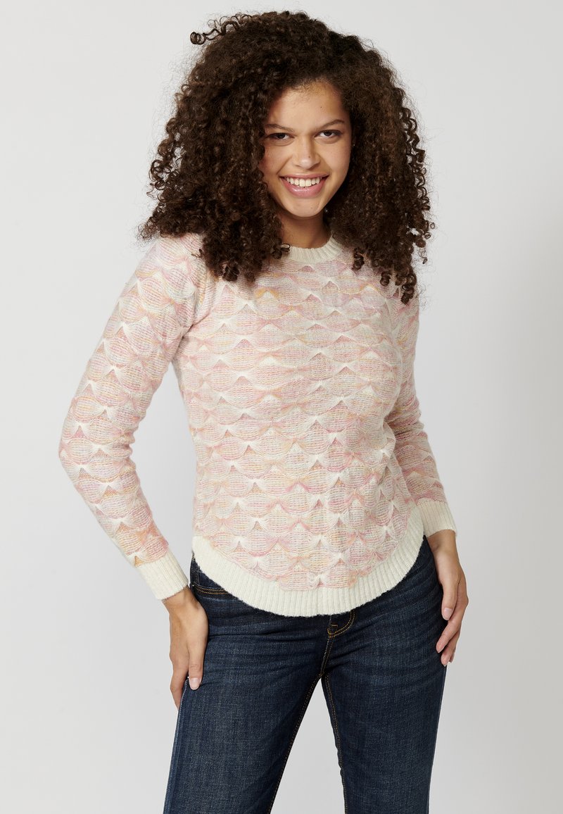 Pull à tricoter avec un motif de vagues dans des teintes pastel douces de rose, blanc et beige. Col et poignets côtelés, coupe décontractée.