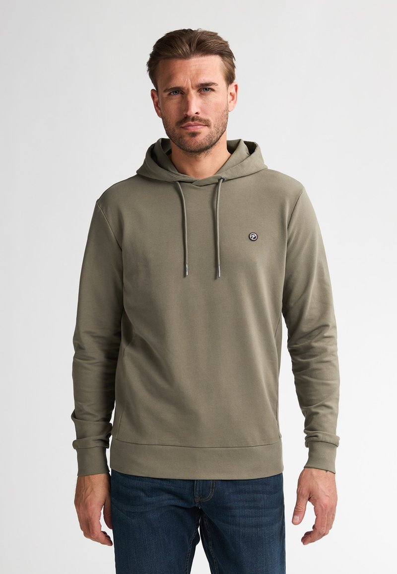 Sudadera verde oliva de manga larga, con capucha ajustable y un pequeño logo en el pecho. Textura suave, diseño ajustado, combinada con jeans azules.