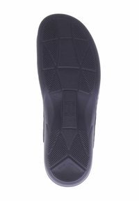 Schwarze Gummisohle mit einer strukturierten Oberfläche, die schräge und horizontale Rillen für besseren Grip aufweist. Leicht erhabenes zentrales Logo-Detail.