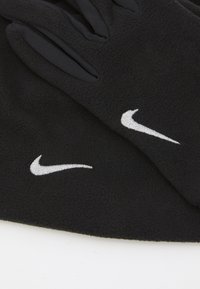 Svarta fleecehandskar med en mjuk yta. Vitt broderat Nike-logga på varje handske. Designade för värme och komfort.