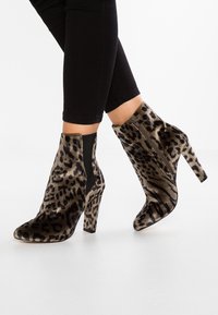 Botas de tobillo con estampado de leopardo, fabricadas en un suave tejido texturizado, con un tacón alto y paneles laterales elásticos para facilitar su uso.