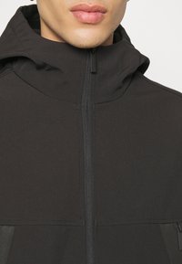 Felpa nera con zip e colletto alto, in tessuto morbido e chiusura frontale a zip. Design minimalista senza motivi o accenti visibili.