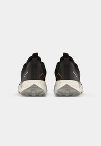 Sportieve schoenen met een zwart en grijs ontwerp, voorzien van een gestructureerde bovenkant, reflecterende accenten en een gespikkelde zool voor grip.