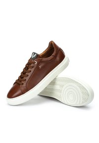 Sneakers in pelle marrone a basso profilo con suole in gomma bianca, punta rotonda e lacci, una scarpa appoggiata inclinata sopra l'altra con la suola rivolta verso l'alto.