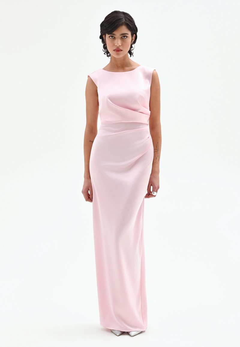 Lange, nauwsluitende jurk van zachte roze satijn. Voorzien van een boothals en subtiele plooien bij de taille. Gladde textuur en een vloerbedekkende lengte.