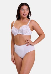 Soutien-gorge en dentelle blanche avec motif floral et bretelles réglables, assorti à une culotte blanche taille haute en tissu lisse.