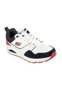 Chaussure de sport blanche avec des accents bleu marine et rouge. La tige présente un mélange de matériaux, y compris du cuir et du suède, avec des détails perforés.
