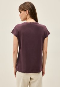 Kortærmet, lilla bomuldsbluse med en afslappet pasform og en struktureret halsudskæring. Ryggen har et enkelt design, der passer godt til lyse bukser.