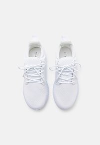 Baskets blanches avec une tige texturée, un bout rond et un design à lacets. Comprend une languette au niveau du talon et une semelle à motif.
