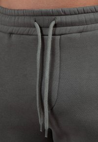 Pantalones de chándal gris oscuro con un tejido texturizado, cinturilla elástica y dos cordones trenzados para un ajuste ajustable.
