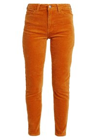 Pomarańczowe spodnie z korduroju o żebrowej fakturze, dopasowany krój, pięć kieszeni oraz zapięcie na guzik z przodu.