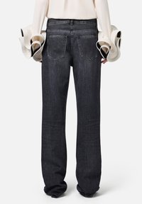 Jeans in denim scuro con una vestibilità rilassata, caratterizzati da un classico design a cinque tasche e una texture sottile, mostrati da dietro.