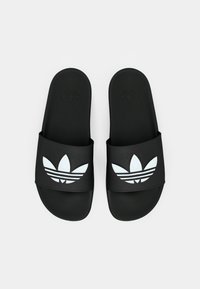 Sandales à glissière noires en caoutchouc lisse, dotées d'une large bride avec un logo Adidas blanc et un motif de feuille. Semelle intérieure texturée pour une meilleure adhérence.