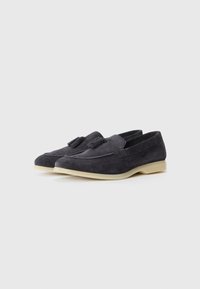 Mørkegrå mockasiner i suede med frynse-detaler, med avrundet tå og lys gummisåle. Glatt tekstur, uformelt design.