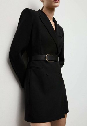 Vestido blazer negro ajustado con mangas largas, botones de doble pecho y una cintura ceñida que presenta un cinturón con detalles dorados. Textura suave.