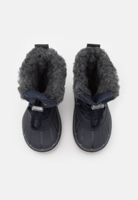 Botas de invierno navy con suelas negras texturizadas y forro suave gris, vistas desde arriba, mostrando los cordones y un ajuste ceñido.