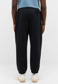 Schwarze Sweatpants mit lockerer Passform, elastischen Bündchen und einer einzelnen Gesäßtasche. Hergestellt aus weichem Material für Komfort und Bewegungsfreiheit.