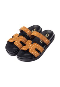 Sandali a infradito in suede tan con suole in gomma nera, caratterizzati da due fasce larghe decorate con borchie e disegni a intaglio.