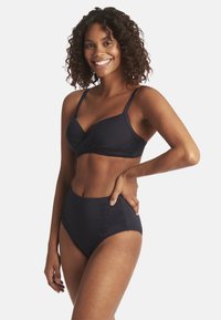Granatowy bikini składający się z topu z zakręconymi miseczkami oraz wysokich majtek z bocznymi marszczeniami dla dodania tekstury.
